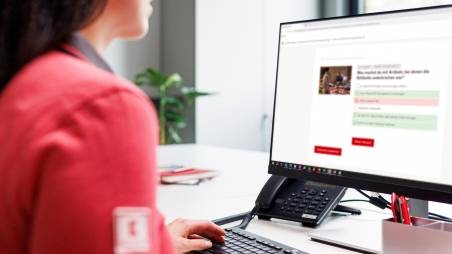 Kaufland-Verkaufsmitarbeiterin am Schreibtisch mit Tastatur und Bildschirm.