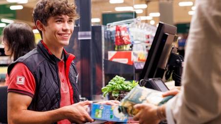 An der Kasse in einer Kaufland-Filiale: Junger Mitarbeiter kassiert den Einkauf einer Kundin.