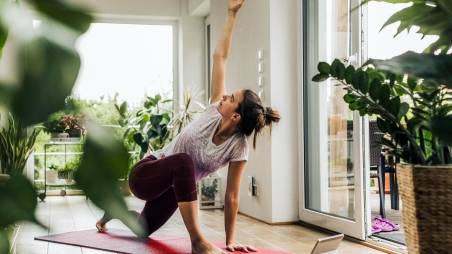 Eine Frau macht zu Hause Yoga auf einer Sportmatte.