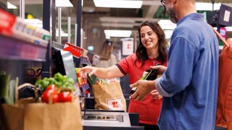 Kaufland-Verkaufsmitarbeiterin hilft einem Kunden an der SB-Kasse.